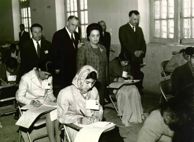  خانم فرخ رو پارسا وزیر آموزش و پرورش دولت هویدا در حال بازدید از جلسه آزمون یکی از مراکز تربیت‌ معلم در استان فارس است.