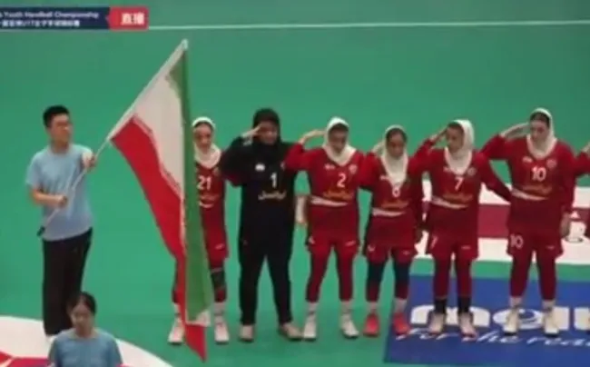  اعضای تیم ملی هندبال نوجوانان دختر ایران قبل از اولین بازی خود در مسابقات قهرمانی آسیا مقابل ژاپن هنگام پخش سرود ایران سلام نظامی دادند.